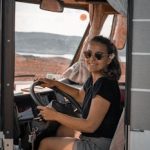 Young woman driving a camper van in scenic Norway landscape. Adventure and travel in style.