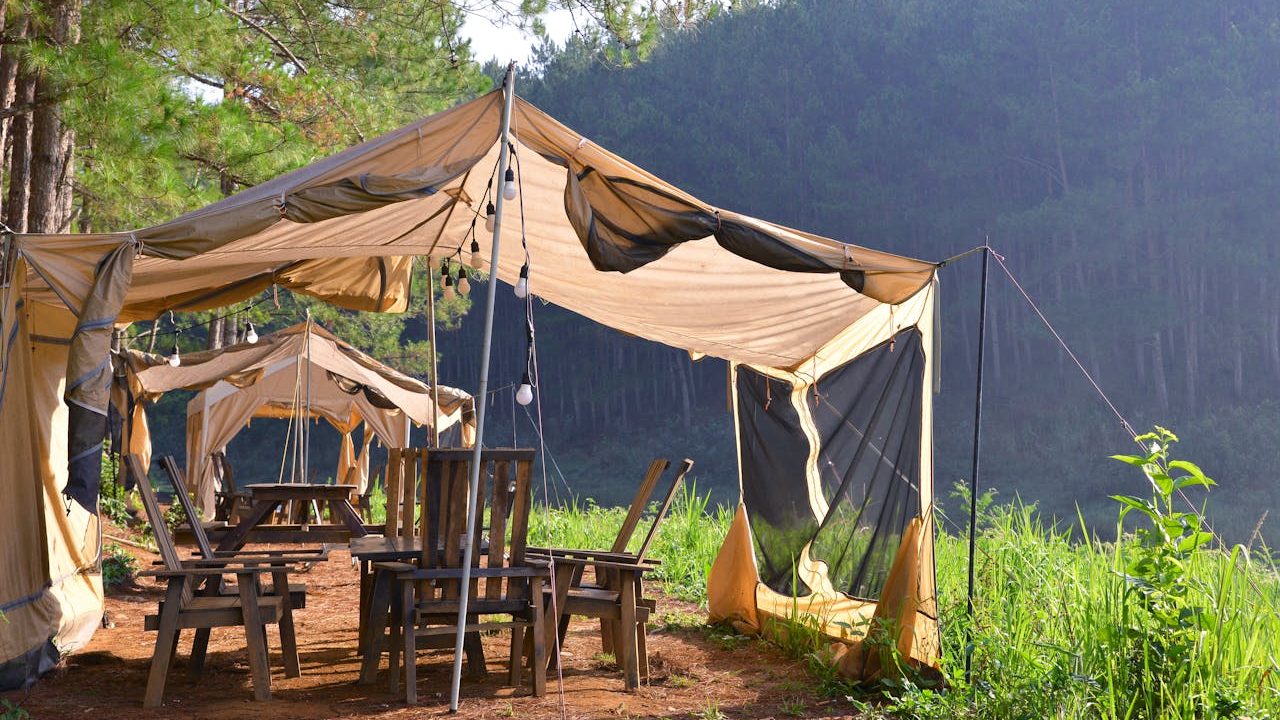'Glamping What Is It?' Showing an example of glamping with a rustic campsite with tents surrounded by lush greenery and serene forest views.