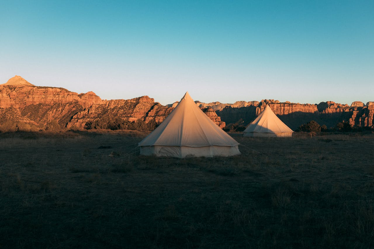 Canvas glamping tents setup in an arid area.