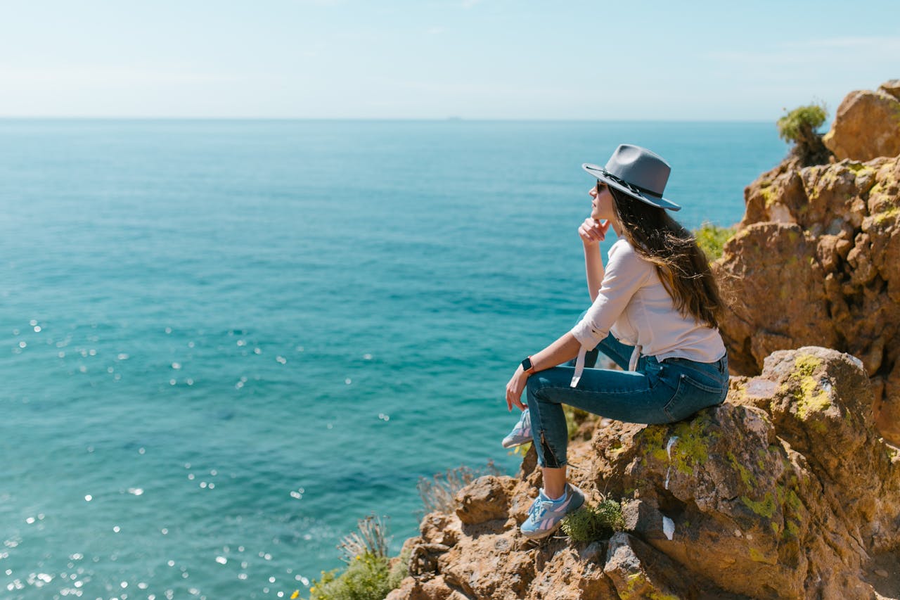 Glamper sitting on rocks by the ocean.