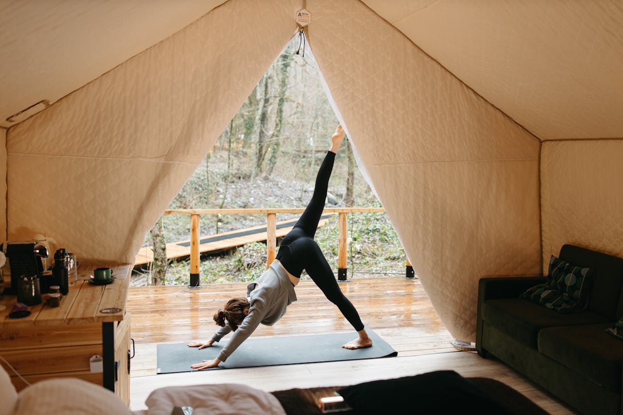 Woman doing yoga in front of her glamping tent.